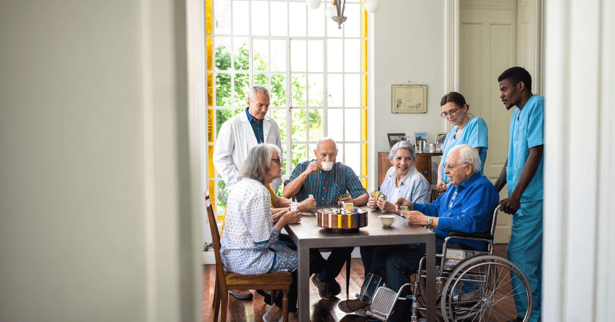 Residents playing cards together with staff nearby